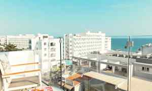 Utsikt från en balkong med stolar och ett bord, med hotellbyggnader och havet i bakgrunden. (AI-genererad text)