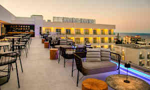 Takbar med sittplatser och utsikt över havet och hotellbyggnader. (AI-genererad text)