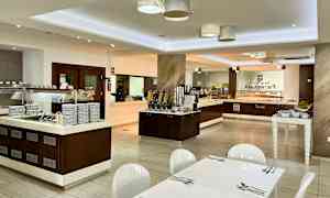 Interiör av en bufférestaurang med matserveringsområden och bord. (AI-genererad text)