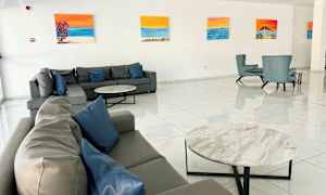 En hotellobby med soffor och fåtöljer, väggarna dekorerade med målningar. (AI-genererad text)