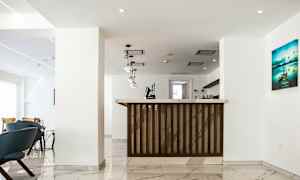 Bild av en ljus och modern hotellreception med marmorgolv, hängande lampor och en receptionsdisk i trä. (AI-genererad text)
