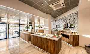 Ett modernt och ljust bufféområde med mat serverad på träställningar och ett dekorerat kaklat väggparti. (AI-genererad text)