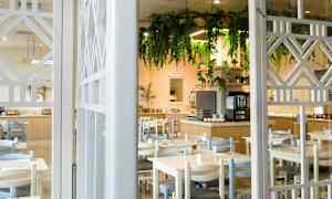 En restaurang med bord och stolar, samt en dekorerad buffé och hängande grönska. (AI-genererad text)