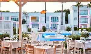 Restaurangbord med vita dukar vid en pool, omgiven av modern arkitektur. (AI-genererad text)