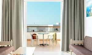 Ett hotellrum med utsikt över en balkong med ett bord och stolar. (AI-genererad text)