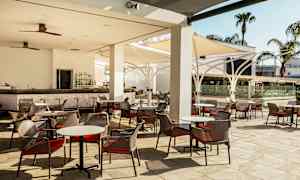 Bild på en utomhusterrass med bord och stolar samt en bar. (AI-genererad text)