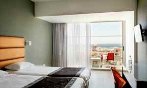 Hotellrum med två enkelsängar och balkong med havsutsikt. (AI-genererad text)