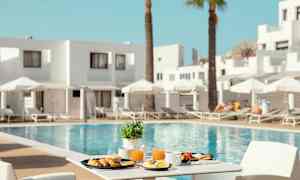 En frukost serverad vid ett bord med utsikt över en pool och solstolar. (AI-genererad text)