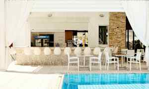 Utomhusbar med vita stolar och bord vid en pool. (AI-genererad text)