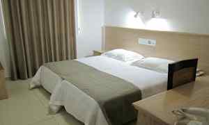 Ett hotellrum med en dubbelsäng, sänglampor och ett bord med telefon. (AI-genererad text)