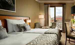 Hotellrum med två bäddar, sittplatser och utsikt över staden. (AI-genererad text)