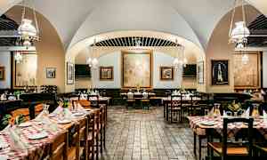 En restaurang inomhus med dukade bord och konstverk på väggarna. (AI-genererad text)