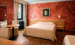 Ett hotellrum med en stor säng och ett bord med stolar, samt en fönster med gardiner. (AI-genererad text)