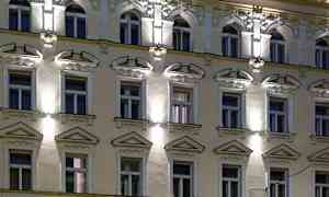 En fasad på en byggnad med flera fönster, dekorationer och belysning under kvällstid. (AI-genererad text)