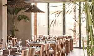 Interiör av en restaurang med träbord, stolar och dekorerade med glas och bestick. (AI-genererad text)