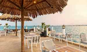 Utomhusservering med solsäkra parasoll nära havet. (AI-genererad text)