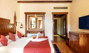 Ett hotellrum med en dubbelsäng som har röda kuddar och en dekoration formad som en svan på sängen. (AI-genererad text)