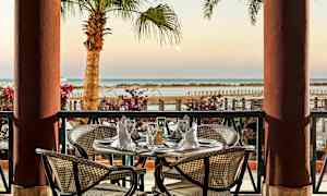 En borddukning på en terrass med utsikt över havet och palmer. (AI-genererad text)