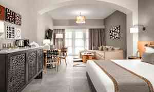 Ett hotellrum med en säng, sittgrupp och matbord, samt modern inredning. (AI-genererad text)