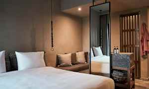 Ett sovrum med en stor säng, kuddar, en soffa och ett högt spegel. (AI-genererad text)