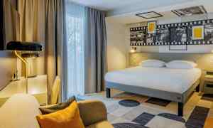 Hotellrum med stor säng, skrivbord och sittplats. (AI-genererad text)