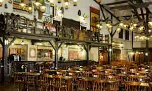 Interiör av en rustik restaurang med träbord och stolar samt dekorationer på väggarna. (AI-genererad text)