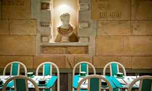 På bilden syns en restaurang med turkosa bord och stolar samt en vit skulptur i en nisch på väggen. (AI-genererad text)