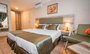 Hotellrum med två bäddar, sängkläder och sängbord med lampa. (AI-genererad text)