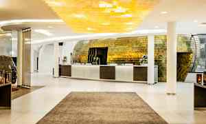 Reception i en modern hotellobby med ett stilfullt gyllene inre och ljus inredning. (AI-genererad text)
