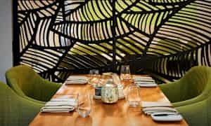 Ett dukat bord med gröna stolar och en dekorativ skärm i bakgrunden. (AI-genererad text)