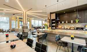 Modern cafémiljö med sittplatser vid bord och bardisk, dekorerad med blommor. (AI-genererad text)