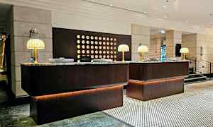 En receptionsdisk i en hotellobby, med marmorskivor och bordslampor. (AI-genererad text)