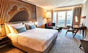 Ett modernt hotellrum med en stor säng, sittmöbler och skrivbord. (AI-genererad text)