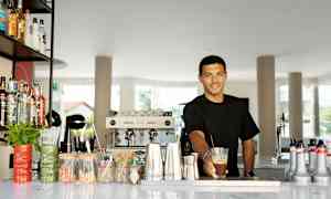 En bardisk med diverse dryckesflaskor, verktyg och serveringstillbehör. (AI-genererad text)