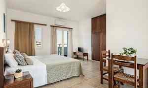 Ett sovrum med en dubbelsäng, ett litet bord med två stolar och en garderob. (AI-genererad text)