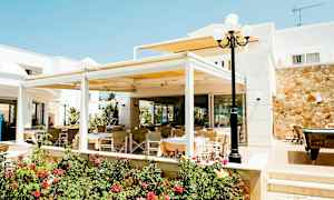 Uteservering med bord och stolar vid en byggnad, omgiven av blommor och växter. (AI-genererad text)