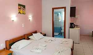 Ett enklare hotellrum med rosa väggar, två enkelsängar och utsikt mot badrumsdörren. (AI-genererad text)