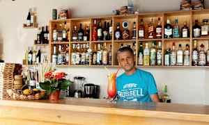 En bar med hyllor fyllda av alkoholflaskor och ett serveringsområde med en färgglad drink. (AI-genererad text)