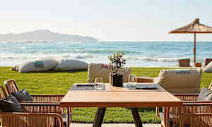 Ett bord med stolar på en terrass med utsikt över havet. (AI-genererad text)