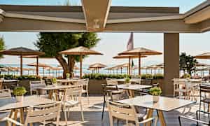 Uteservering med utsikt mot en strand och parasoller. (AI-genererad text)