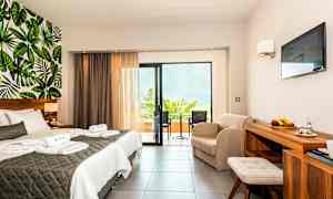 Ett hotellrum med dubbelsäng, sittgrupp, balkong och väggdesign med bladmotiv. (AI-genererad text)