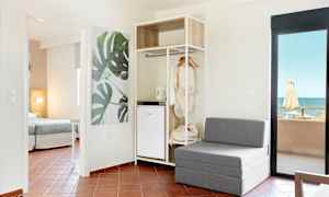 Modernt hotellrum med sittmöbler, öppet klädskåp och havsutsikt. (AI-genererad text)