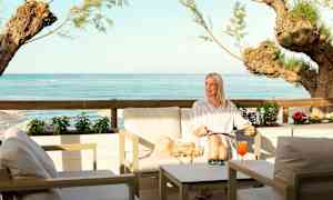 En sittgrupp vid havet med utsikt över blått vatten och träbarr. (AI-genererad text)