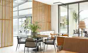 Interiör av ett modernt rum med bord, stolar och fönster. (AI-genererad text)