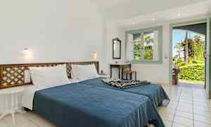 Ett sovrum med en dubbelsäng, ett bord och en öppning mot en grönskande trädgård. (AI-genererad text)