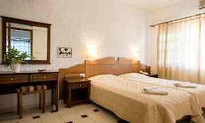 Ett hotellrum med två separata sängar, en träbyrå och vita väggar. (AI-genererad text)