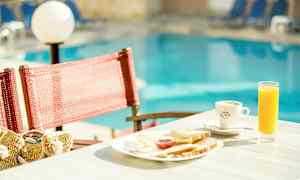 En frukostbricka med juice och kaffe på ett bord vid en pool. (AI-genererad text)