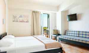 Ett hotellrum med en säng, en soffa, en TV och en balkong. (AI-genererad text)