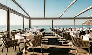 Restaurang med havsutsikt, eleganta möbler och dukade bord. (AI-genererad text)