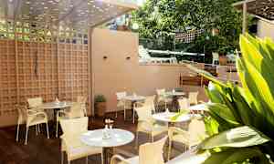 En terrass med bord och stolar, omgiven av grönska. (AI-genererad text)